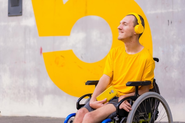Retrato de uma pessoa com deficiência vestida de amarelo em uma cadeira de rodas ouvindo música