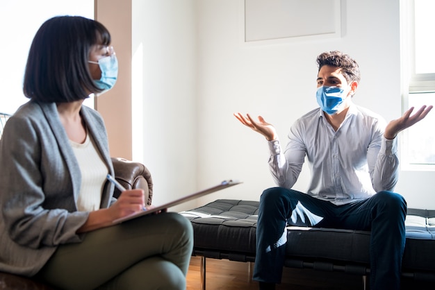 Retrato de uma psicóloga conversando com seu paciente e fazendo anotações durante uma sessão de terapia