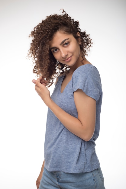 Retrato de uma raça misturada da mulher negra bonita com penteado desgrenhado. Menina afro-americana de sorriso no estúdio em um fundo branco.