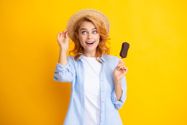 Retrato de uma ruiva com sorvete de chocolate em fundo amarelo Mulher alegre encaracolada comendo