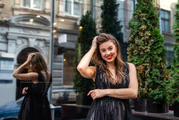 Retrato de uma senhora bonita em um vestido preto de noite ao ar livre. estilo de vida da cidade