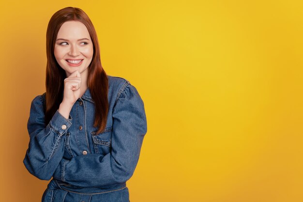 Retrato de uma senhora criativa e criativa com o dedo queixo olhando o espaço vazio no fundo amarelo