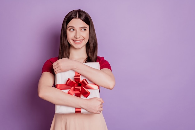 Retrato de uma senhora encantadora curiosa segurar um abraço e olhar um espaço em branco no fundo violeta