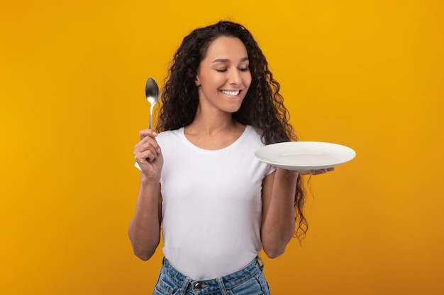 Foto retrato de uma senhora latina sorridente segurando a colher e o prato