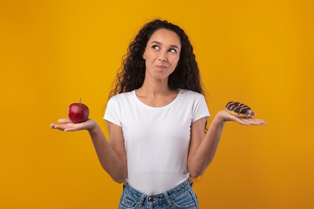 Foto retrato de uma senhora latina sorridente segurando maçã e rosquinha