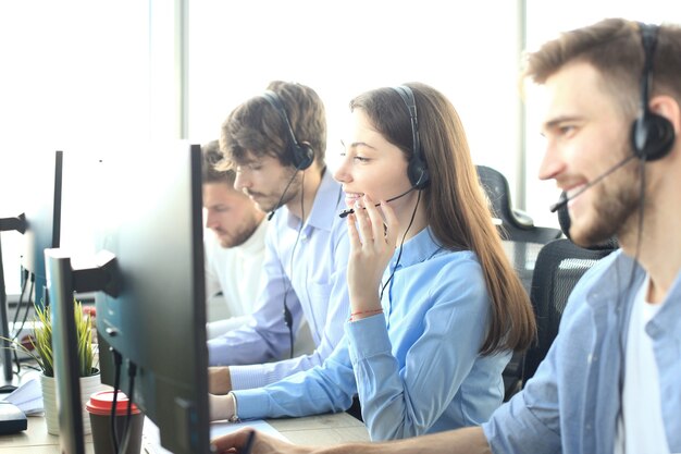 Retrato de uma trabalhadora de call center acompanhada por sua equipe. Operador de suporte ao cliente sorridente no trabalho.