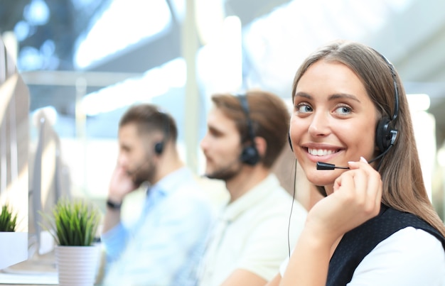 Retrato de uma trabalhadora de call center acompanhada por sua equipe. Operador de suporte ao cliente sorridente no trabalho.