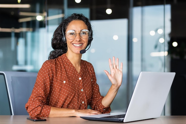 Retrato de uma trabalhadora de suporte técnico bem-sucedida, hispânica, com cabelo encaracolado, sorrindo e olhando para