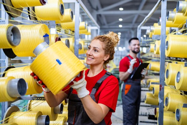 Retrato de uma trabalhadora mudando o rolo de fio em uma máquina de tricotar dentro de uma fábrica têxtil