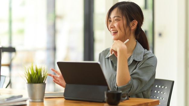Retrato de uma trabalhadora sorrindo e conversando com sua colega de trabalho enquanto trabalhava com um tablet digital