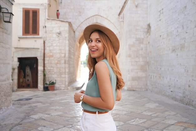 Retrato de uma turista atraente sorridente caminhando sozinha na cidade medieval de Barletta Apulia Itália