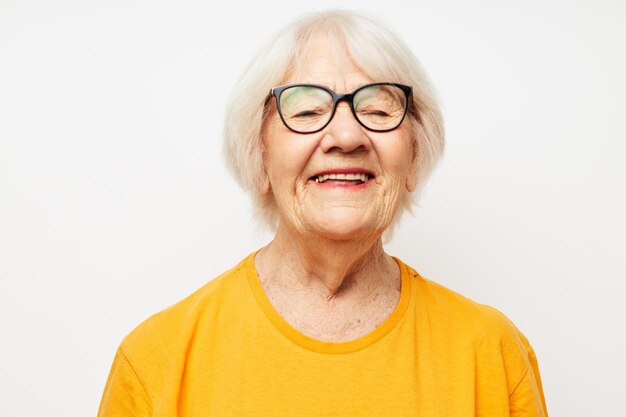 Retrato de uma velha amigável em camiseta casual e óculos isolados de fundo