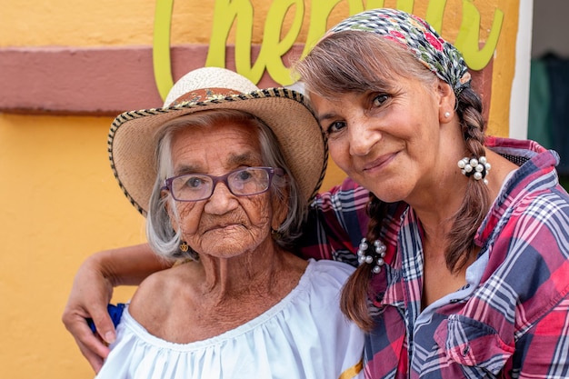 Retrato de uma velha camponesa com sua filha sorridente vestindo roupas típicas colombianas Mulheres com pele morena