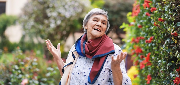 Retrato de uma velha feliz sorrindo aproveitando a aposentadoria usando cachecol colorido em belo jardim