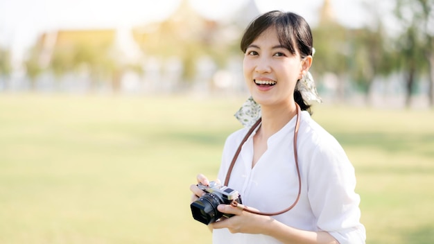 Retrato de uma viajante asiática usando câmera conceito de férias de turismo de verão na Ásia com o grande palácio em um fundo em Bangkok Tailândia