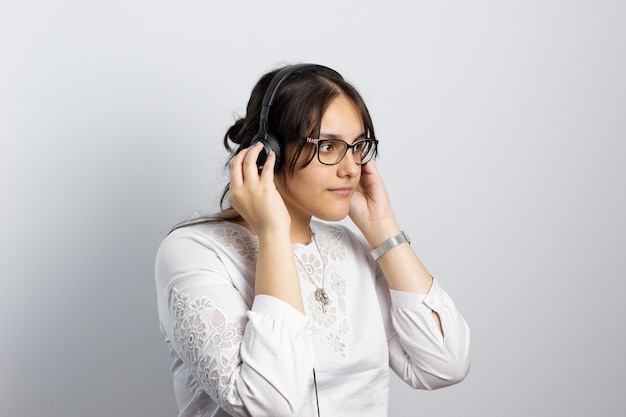 Retrato de una chica jovem escuchando musica con cascos sobre un fondo blanco