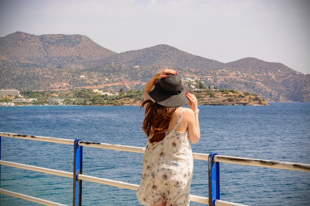 Retrato de verão ao ar livre de uma jovem mulher bonita olhando para o mar no porto de Agios Nikolaos