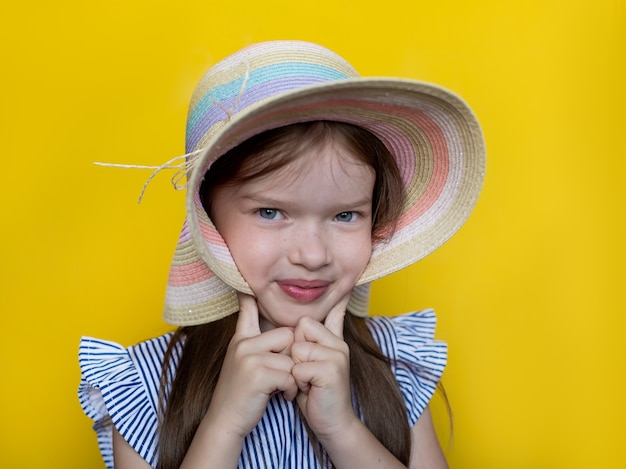 Foto retrato de verão de uma linda garotinha fofa com um chapéu e vestido o conceito de uma moda infantil de férias de verão