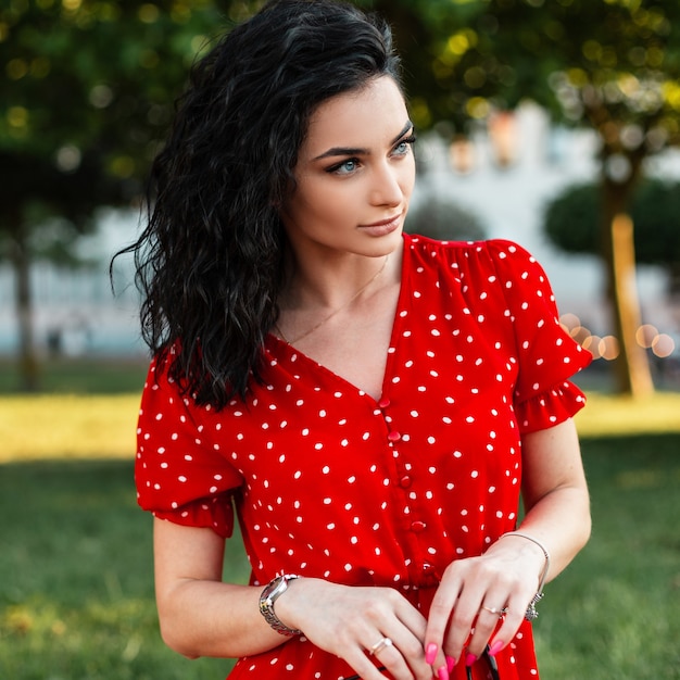 Retrato de verão de uma linda jovem cacheada em um vestido vintage vermelho na moda