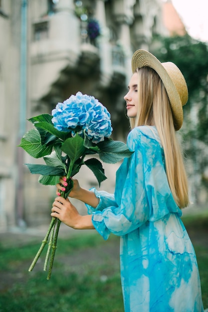 Retrato de verão de uma linda mulher caminhando pelas ruas com flores de hortelã