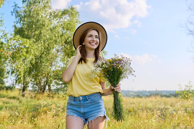 Retrato de verão de uma mulher feliz de 30 anos com buquê de flores silvestres