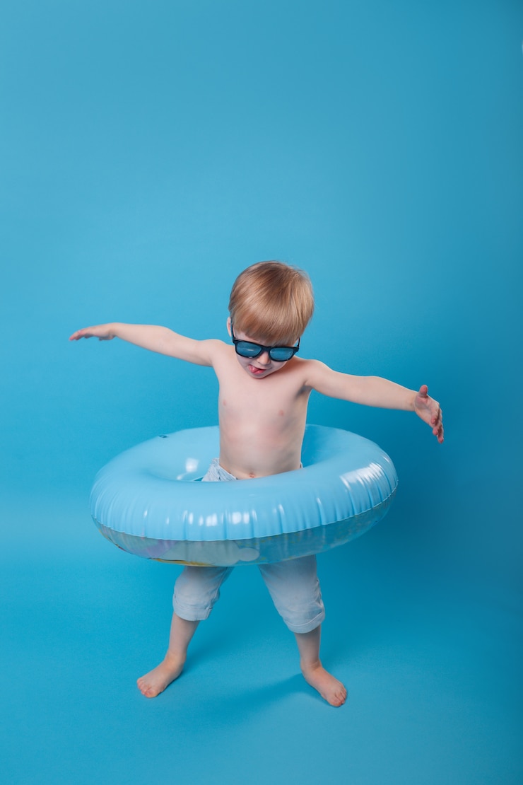 Foto retrato de verão do menino com óculos escuros e anel inflável em fundo azul