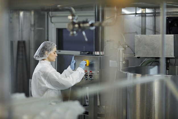 Foto retrato de vista lateral de operária operando unidades de máquinas em uma fábrica de produção de alimentos limpos, copie o espaço