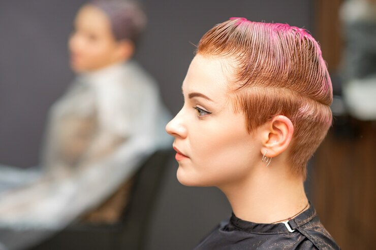 Foto retrato de vista lateral de uma bela jovem caucasiana com um corte de cabelo curto rosa esperando por um cabeleireiro em um salão de beleza