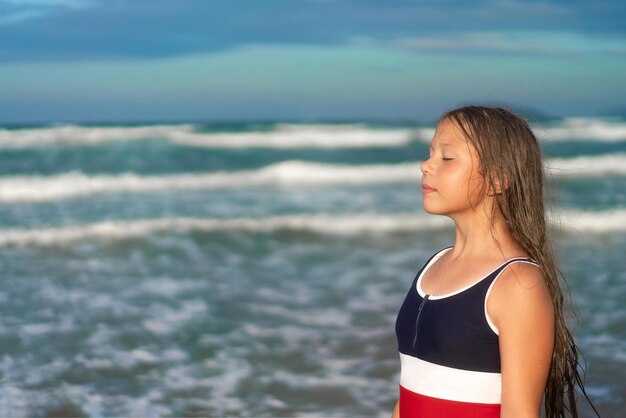 Retrato de vista lateral de uma garota feliz respirando ar fresco na praia ou lago Foto de alta qualidade