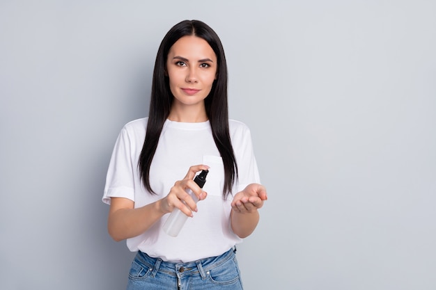 Retrato dela, ela é simpática, atraente, adorável, bonita, saudável, cabelos retos, menina, usando spray anti infecção sars prevenção estéril mãos limpas isoladas sobre fundo cinza claro pastel