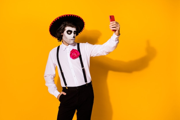 Foto retrato dele, ele bonito pintado assustador sério cara imponente namorado caballero tomando fazendo selfie calavera catrina look outfit isolado brilhante vívido brilho vibrante fundo de cor amarela