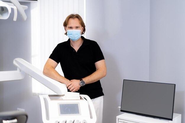 Retrato del dentista profesional. Doctor con máscara. Doctor posa cerca de equipos profesionales.