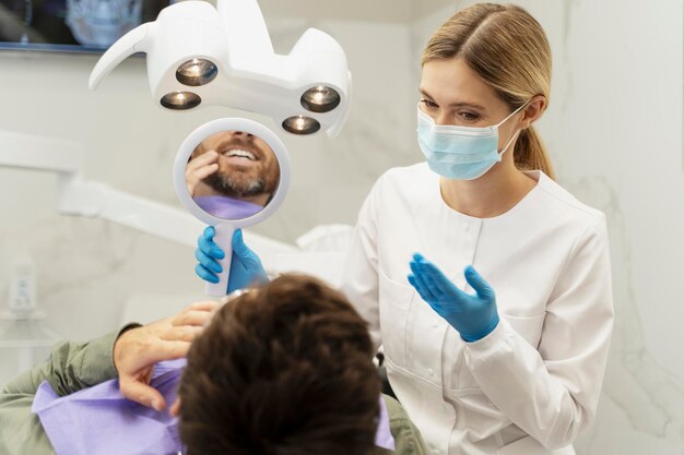 Foto retrato de un dentista que lleva una máscara de protección en una consulta con un paciente