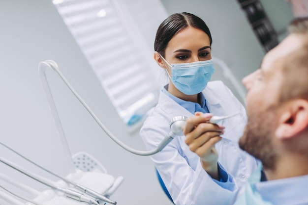 Retrato del dentista que trata los dientes del paciente en la clínica dental moderna