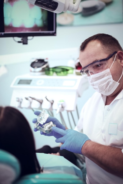 Foto retrato de un dentista que trata los dientes de una paciente joven