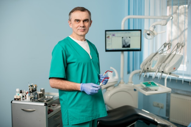 Retrato del dentista de sexo masculino hermoso en la oficina dental de morden. Odontología