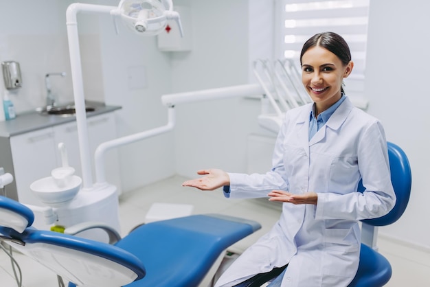 Retrato de una dentista sonriente que muestra su lugar de trabajo en una clínica médica moderna