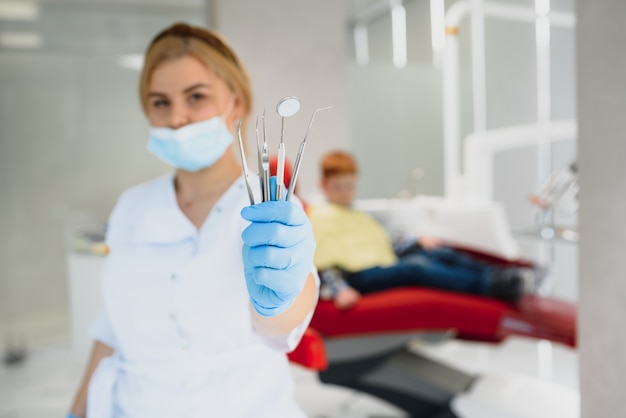 Retrato de un dentista sosteniendo instrumentos dentales en sus manos en el primer plano de la clínica