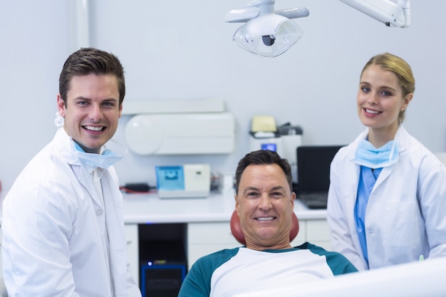 Retrato de dentistas sonrientes y paciente masculino