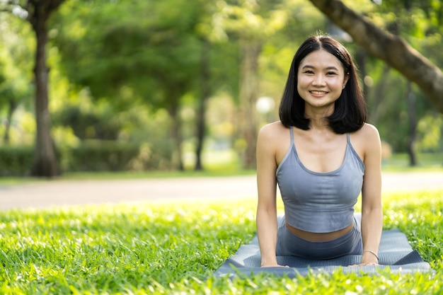 Retrato deporte asiático belleza cuerpo delgado mujer en ropa deportiva sentado relajarse y niña practicando yoga y hacer ejercicio físico en el parque en casaDieta conceptoFitness y saludable