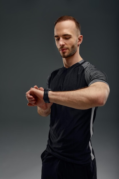 Retrato de deportista comprobando la frecuencia cardíaca en fitness trekker después de entrenar en el gimnasio