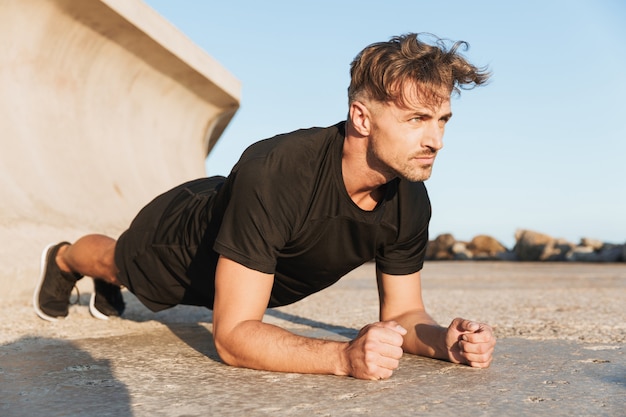 Retrato de un deportista concentrado haciendo ejercicio de plancha