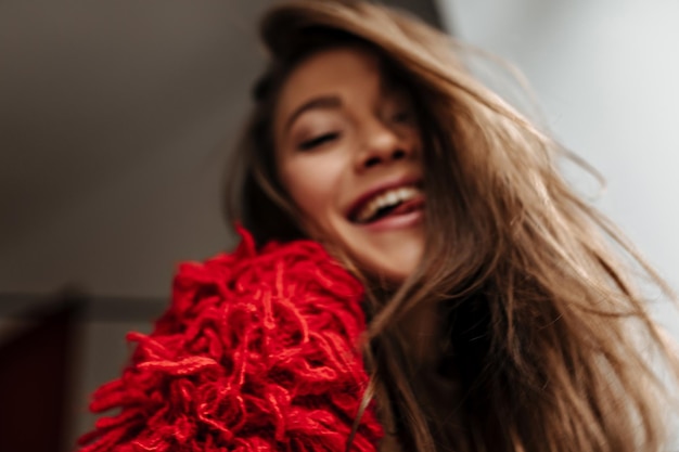 Retrato desfocado de menina morena com cabelo liso, vestido de camisola vermelha, mostrando a língua