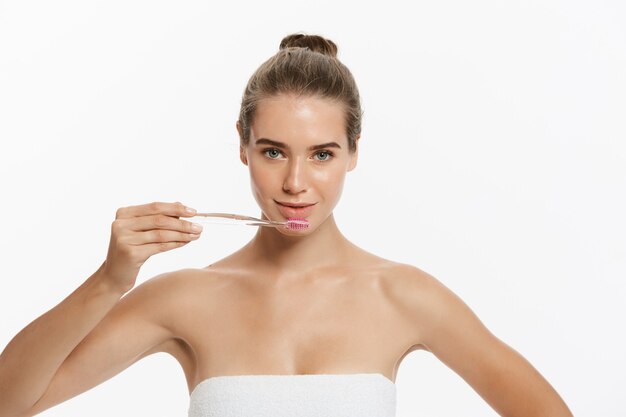 Retrato de los dientes que aplican con brocha hermosos de la mujer joven.