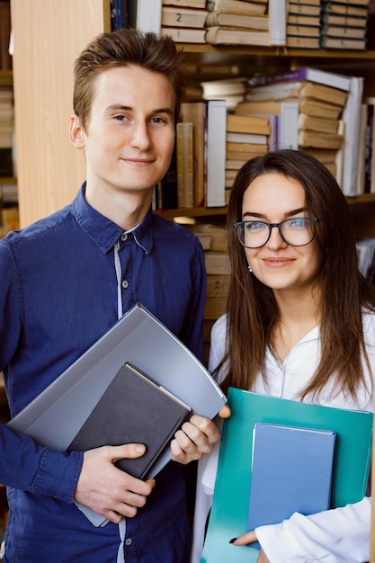 Retrato de diligentes estudiantes que estudian en la biblioteca mirando a la cámara