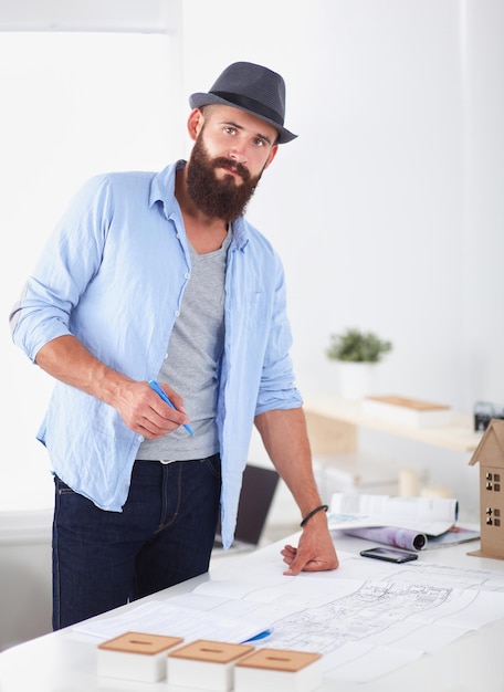 Retrato de diseñador masculino con planos en el escritorio de la oficina.