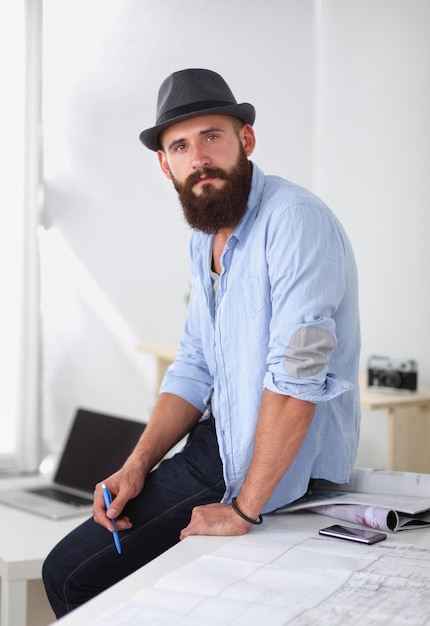 Retrato de diseñador masculino con planos en el escritorio de la oficina.