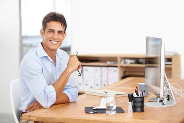 Foto retrato de diseño web o hombre feliz con computadora para soporte de ti con tecnología para proyecto o solución negocios sonrientes o programación de empleados orgullosos con gafas o investigación en línea en el escritorio de la oficina