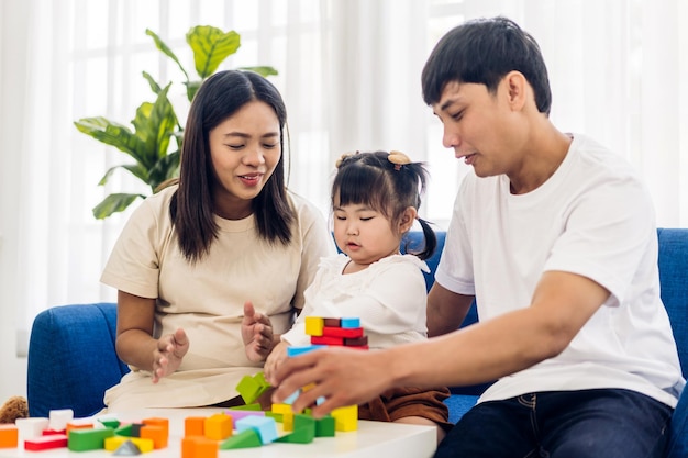 Retrato de disfrutar del amor feliz familia asiática padre y madre con una niña asiática sonriente actividad aprender y entrenar el cerebro jugar con juguetes construir bloques de madera juego de educación en casa