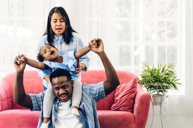 Retrato de disfrutar del amor feliz familia negra padre y madre afroamericanos con una niña africana sonriendo y jugando a divertirse momentos buenos momentos en la habitación en casa